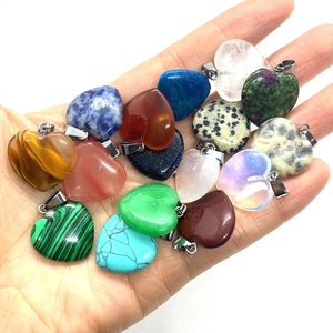 Natural heart-shaped gemstone pendants including tiger eye and turquoise held in hand