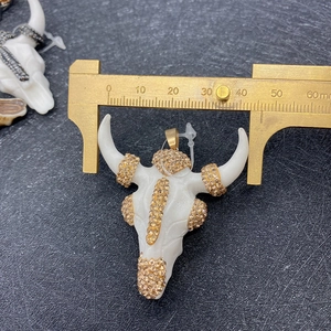 Bull head pendant measurement showing 38mm width with calipers on acrylic stone