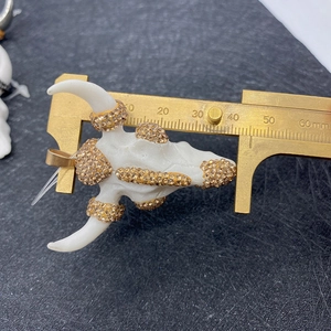 Detailed view of white acrylic bull head pendant with amber crystals measuring 50mm
