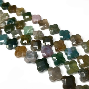Dettaglio macro di perle in pietra naturale sfaccettate a forma di quadrifoglio