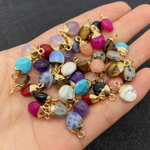Diverse edelsteen hangers met gouden oogjes getoond in een hand voor maatindicatie