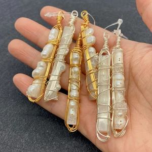 Close-up of handmade cylindrical crystal and pearl pendants with gold wire wrapping