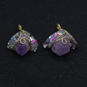 Macro detail of handmade gold wire wrapped amethyst crystal pendants with shell stones