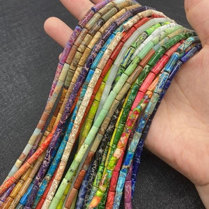 Cuentas cilíndricas de piedra emperador de colores sostenidas para joyería