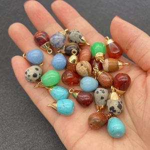 Mix of teardrop natural stone pendants with gold plated caps held in hand for jewelry DIY
