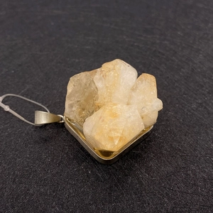 Irregular natural citrine crystal pendant in a square metal base on black background