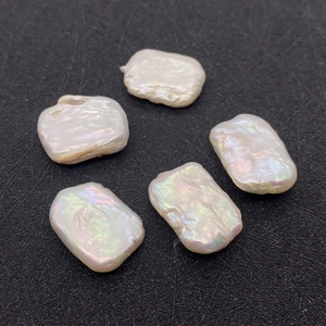 Makro-Detail von fünf rechteckigen Barock-Süßwasserperlen mit Regenbogen-Lüster auf Schwarz