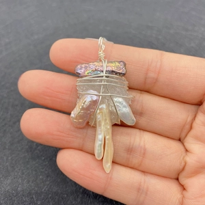 Detailed close-up of handmade wire-wrapped baroque pearl pendant with natural stone crystals