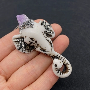 Detailed macro view of white elephant pendant with purple amethyst stone and crystal accents