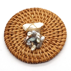 Handmade baroque pearl wire-wrapped pendant with natural shell accents on a rattan mat