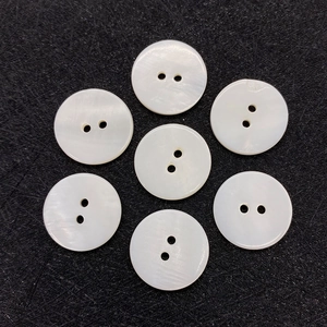 Detail view of seven natural white mother of pearl 2-hole round buttons with iridescent sheen