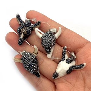 Bull skull pendant with hand-set grey rhinestones and silver metal clasp held in hand