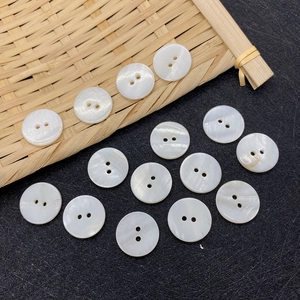 Detailed view of natural white shell buttons with iridescent luster on textured black surface