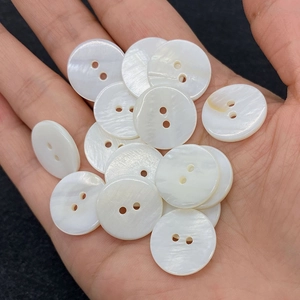 Natural white shell flower buttons held in hand showing iridescent pearl luster