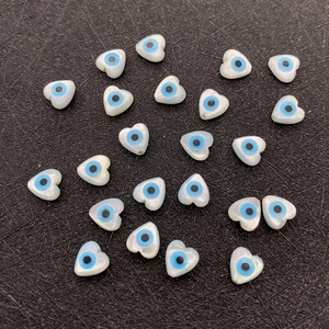 Macro shot of 6mm heart-shaped evil eye shell beads with iridescent mother of pearl finish