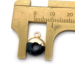 Macro-weergave van een 10 mm zwart-gouden ronde hanger gemeten met een schuifmaat