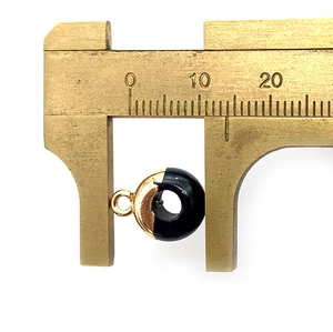 Detail van een 10mm zwarte onyx hanger gemeten met een messing schuifmaat op wit