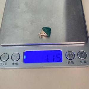 Ψηφιακή ζυγαριά που δείχνει βάρος 1,15g για ένα μενταγιόν από πράσινη πέτρα και χρυσό