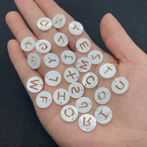 Gros plan de perles alphabet en nacre naturelle sur une paume pour bijoux DIY