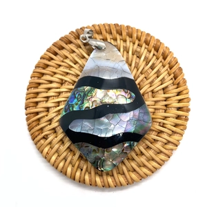 Macro shot of teardrop abalone shell pendant with silver clasp on woven mat