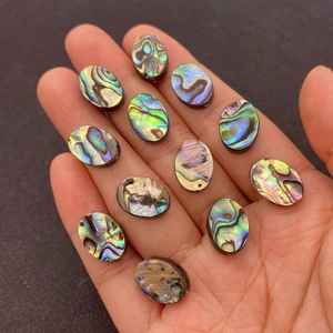 Detailed macro view of 12 natural iridescent oval abalone shell cabochons for jewelry making