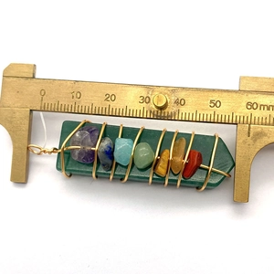 Detailweergave van handgemaakte stenen hanger met chakra-kralen en schuifmaat meter