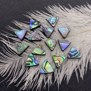 Makro-Detail von 13mm Dreieck-Abalone-Muschelperlen mit natürlichem Perlmuttglanz auf Feder