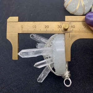 Macro shot showing 35mm width measurement of white crystal pendant with silver wire wrap