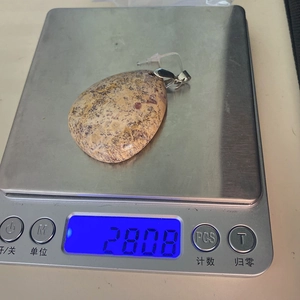 Vue détaillée d'un pendentif en pierre naturelle de 28,08g sur une balance numérique
