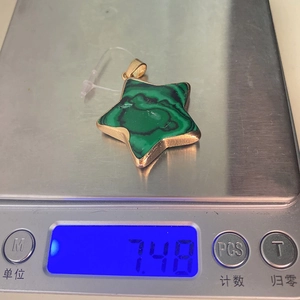 Detailansicht eines Malachit-Sternanhängers mit 7,48g Gewicht auf einer Digitalwaage