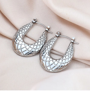 Detailed close-up of silver U-shaped titanium earrings with textured diamond-pattern finish