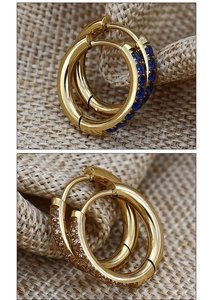 Macro view of gold hoop earrings with inlaid blue and champagne zircon gemstones