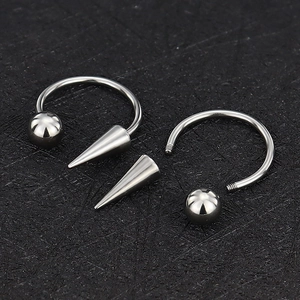 Anello a ferro di cavallo in acciaio lucido con sfera e punta su sfondo nero