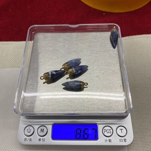 Macro shot showing five bullet-shaped blue stone pendants on a digital scale