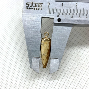 Macro view measuring a bullet-shaped natural stone pendant with a digital caliper