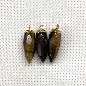 Macro detail of bullet shaped tiger eye stone pendants with golden metal caps