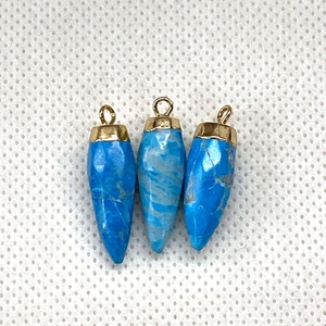 Detailed macro view of bullet-shaped turquoise stone pendants with golden metal caps