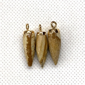 Macro detail of faceted natural stone pendants with polished gold metal caps and loops