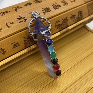 Macro shot of 7 chakra gemstones on a purple crystal pillar pendant with silver frame