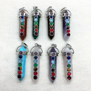 Polished hexagonal crystal healing stone pendants with seven chakra stones on light fabric
