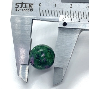 Macro view of Ruby in Zoisite gemstone bead being measured with a metal caliper