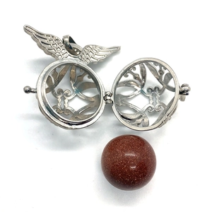 Detailed view of silver angel wing cage pendant with sparkling red goldstone bead