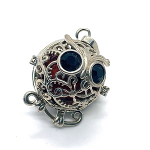 Vue détaillée d'un pendentif hibou argenté avec yeux en gemme noire et sphère