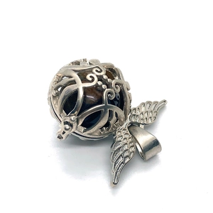 Detailed macro view of silver hollow sphere pendant with wings and polished tiger eye stone