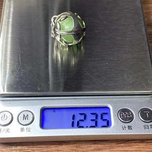 Hohlkugel Anhänger mit grünem Stein auf einer Waage mit Anzeige von 12,35 g Gewicht