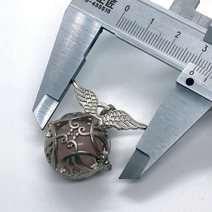 Detailed view of silver angel wing pendant with pink stone being measured by a caliper