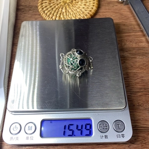 Vue détaillée d'un pendentif hibou en turquoise pesé sur une balance, affichant 15,49 g