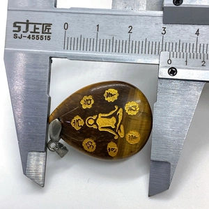 Measuring the 30mm width of a tiger eye stone teardrop pendant with a metal caliper