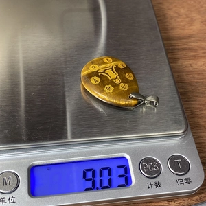 Tiger eye stone teardrop pendant showing weight of 9.03g on digital scale