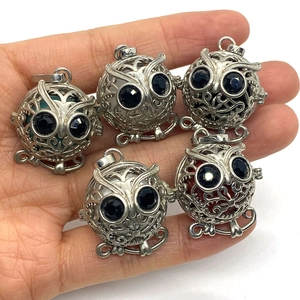 Pendentifs hibou argentés ajourés avec sphères en pierre naturelle dans la main